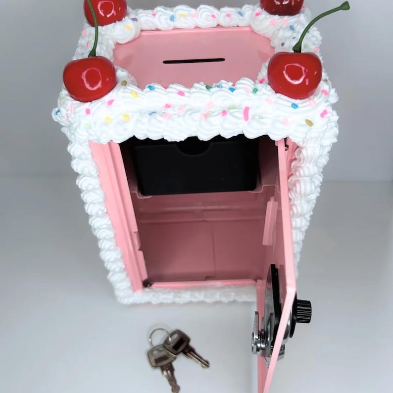Top pink cake vault mini locker showing basket for coins, spacious bottom compartment for cash or jewelry, and key.