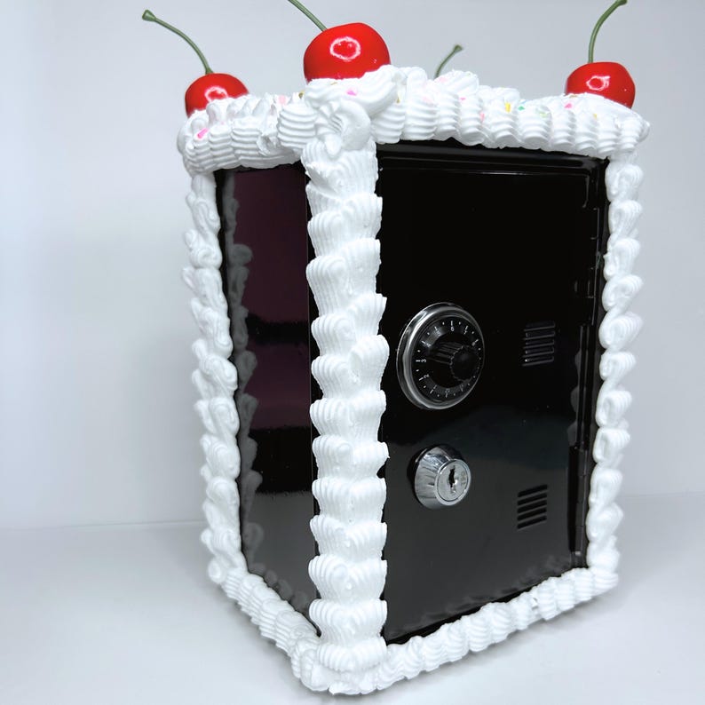 Front view of the black cake vault mini locker with white frosting outlines, rainbow sprinkles, and cherries on top.