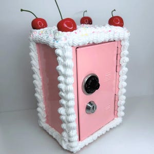 Pink cake vault mini locker with white frosting design, rainbow sprinkles, and cherries on top.