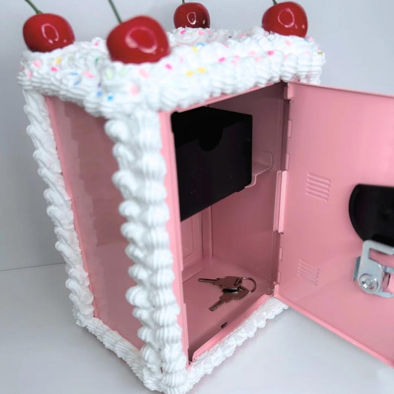 Open pink cake vault mini locker showing basket for coins and spacious bottom compartment for cash or jewelry.