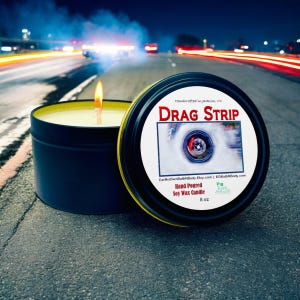 May include: A black and yellow candle tin with the text "DRAG STRIP" and a photo of a tire spinning on a drag strip. The candle is hand-poured soy wax and is 8 ounces.