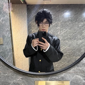 May include: A black school uniform jacket with gold buttons and white trim. The person in the image is wearing a black wig and glasses, holding a black phone in front of a mirror.