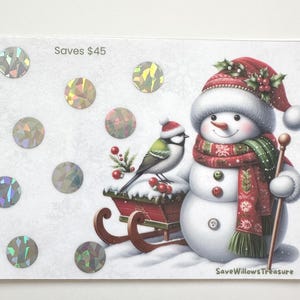 May include: A holiday-themed card featuring a snowman with a red hat and scarf, holding a walking stick. A bird sits on a sled with berries. The card has holographic circles and the text "Saves $45".