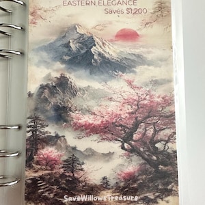 May include: A rectangular planner insert featuring a landscape illustration of a snow-capped mountain, a red sun, and blooming cherry blossom trees. The text reads: Visions of Japan: EASTERN ELEGANCE Saves $1,200 and SaveWillowsTreasure.