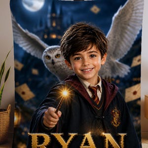 May include: A rectangular fleece blanket featuring a printed graphic of a young person in a dark wizard robe holding a glowing wand. A large white owl flies behind them against a dark castle background with floating letters. The name RYAN is in gold.