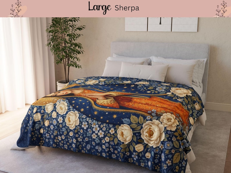 May include: A large Sherpa blanket with a floral design featuring a central figure in orange and gold, surrounded by white roses and blue flowers on a navy blue background. The blanket is draped over a bed with white pillows.