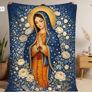 May include: A blue blanket featuring a religious illustration of a woman with a gold halo, wearing a blue cloak and orange dress. The blanket is decorated with white flowers and the text "DESIGN 3".