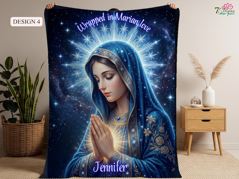 May include: A blue blanket featuring an illustration of a woman in a blue veil with hands clasped in prayer. The blanket has the text "Wrapped in Marian love" and the name "Jennifer". The background is a starry night.