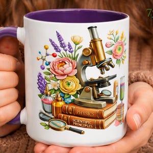 Op de afbeelding: Een witte keramische mok met een paarse binnenkant en handvat, voorzien van een kleurrijke afbeelding van een microscoop, twee op elkaar gestapelde boeken met de tekst Physics en Scientific Principles, een vergrootglas, bloemen en een molecuulmodel.