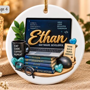 Może przedstawiać: Okrągła biała ceramiczna ozdoba z laptopem wyświetlającym kod i imię Ethan, czarnym kubkiem z napisem Eat Code Coffee Repeat, stosem książek o tytułach Python, Javascript, Cloud i AI, czarnymi okularami oraz myszką komputerową.