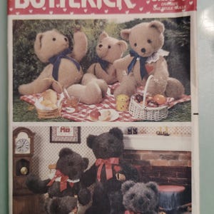 Könnte beinhalten: Eine Butterick Craft Schnittmusterhülle 5627 mit Abbildungen von Teddybären. Der obere Teil zeigt drei hellbraune Bären auf einer Picknickdecke. Der untere Teil zeigt drei dunkelbraune Bären mit roten Schleifen in einem Raum mit einer Spielzeugeisenbahn.