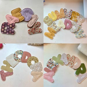 May include: A collection of colorful, fabric-covered letters spelling out various words. The letters feature a variety of patterns, including floral, polka dots, and stripes, in shades of pink, yellow, and green. The letters are arranged in a curved shape.