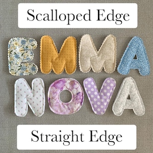 May include: Fabric letters spelling "EMMA NOVA" in various patterns and colors, including floral, polka dot, and solid hues. The letters are displayed with the text "Scalloped Edge" and "Straight Edge" above and below.