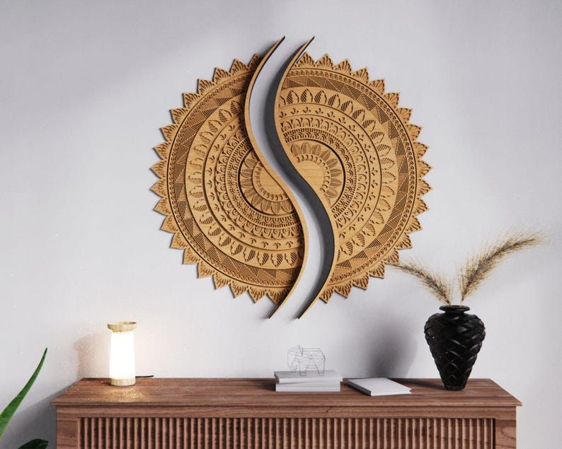 May include: A large, intricately carved wooden wall art piece in a sunburst design, split by a curved, light-colored element. The artwork is mounted on a white wall above a wooden cabinet with a lamp and a black vase.