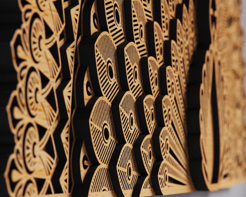 May include: A layered wooden wall art piece featuring a peacock feather design. The artwork has a natural wood color with black accents, creating a three-dimensional effect. The intricate cut-out patterns add depth and visual interest.