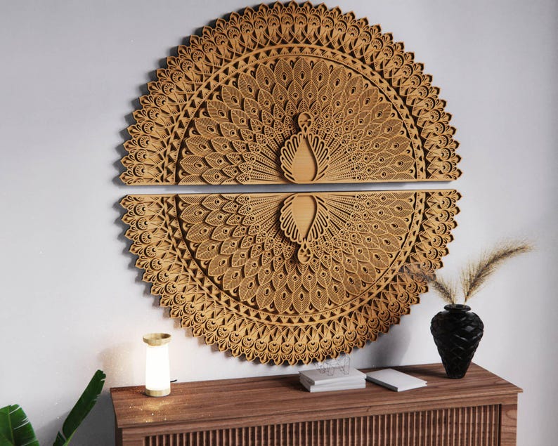 May include: Two-piece, laser-cut wooden wall art depicting a peacock with its tail feathers fanned out. The artwork is a light brown color and features intricate details. The peacock's body is in the center of the design. The artwork is mounted on a white wall.