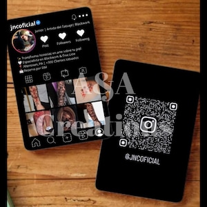 Puede incluir: Dos tarjetas digitales negras con el perfil de Instagram @JNCOFICIAL. Una tarjeta muestra un perfil con imágenes de tatuajes y texto. La otra tarjeta tiene un código QR para el perfil de Instagram. Las tarjetas están sobre una superficie de madera.