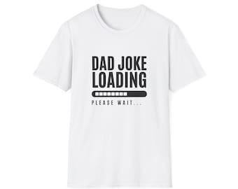 May include: White t-shirt with the text "DAD JOKE LOADING" in bold black letters above a loading bar graphic. Below the graphic, the text "PLEASE WAIT..." is printed in black.