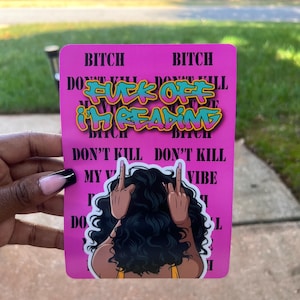 May include: A pink rectangular sticker with the words "BITCH" and "DON'T KILL MY VIBE" printed on it. The sticker features the text "FUCK OFF I'M READING" in a graffiti style font, and an illustration of a woman with her back turned, flipping the middle finger.