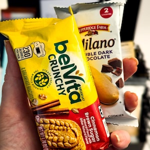 Op de afbeelding: Een gele verpakking belVita Crunchy Cinnamon Brown Sugar ontbijtkoekjes en een witte verpakking Pepperidge Farm Milano Double Dark Chocolate koekjes. De belVita-verpakking toont 230 calorie&euml;n en 4 koekjes, terwijl de Milano-verpakking 2 koekjes toont.