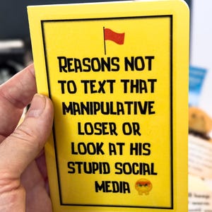 Puede incluir: Una tarjeta amarilla con texto negro que dice "RAZONES PARA NO ENVIAR MENSAJES DE TEXTO A ESE PERDEDOR MANIPULADOR O MIRAR SUS EST&Uacute;PIDAS REDES SOCIALES" con una bandera roja y un emoji de cara enfadada. La tarjeta est&aacute; sujeta por una mano.