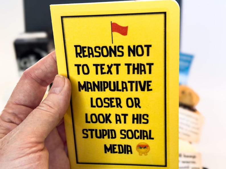 Puede incluir: Una tarjeta amarilla con texto negro que dice "RAZONES PARA NO ENVIAR MENSAJES DE TEXTO A ESE PERDEDOR MANIPULADOR O MIRAR SUS EST&Uacute;PIDAS REDES SOCIALES" con una bandera roja y un emoji de cara enfadada. La tarjeta est&aacute; sujeta por una mano.