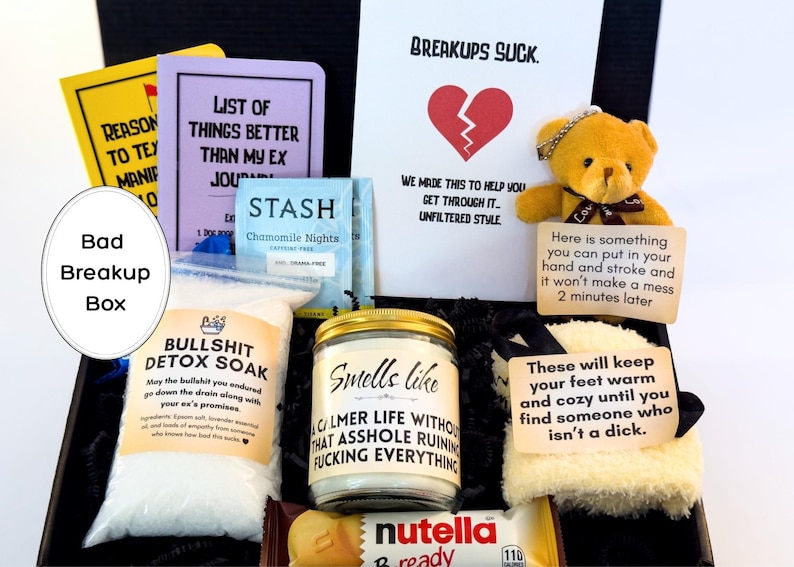 Puede incluir: Una caja negra llena de art&iacute;culos de recuperaci&oacute;n de rupturas. Incluye un diario, t&eacute;, sales de ba&ntilde;o, una vela, un osito de peluche y un snack de Nutella. La caja tiene el texto "Bad Breakup Box".