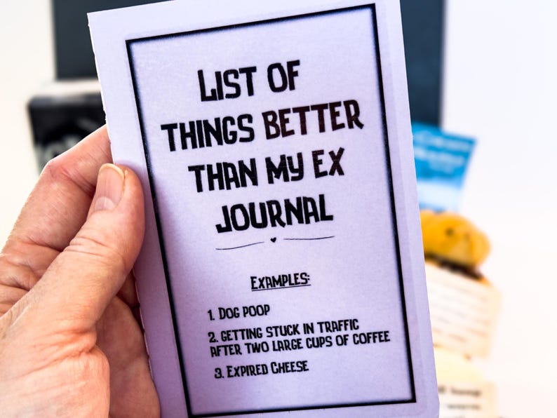 Puede incluir: Una tarjeta blanca con borde negro y texto que dice "LISTA DE COSAS MEJORES QUE MI EX DIARIO." Se enumeran ejemplos como "CACA DE PERRO", "ATASCARSE EN EL TR&Aacute;FICO" y "QUESO CADUCADO."