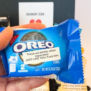 Puede incluir: Un paquete azul de galletas Oreo con el logo de Oreo y el texto "These are better when separated JUST LIKE YOU. Fuck him." El paquete contiene dos galletas y pesa 22g.