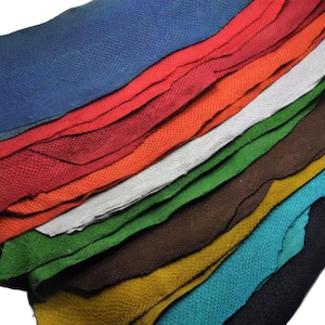 Peut inclure: Une pile de feuilles de cuir multicolores présentant une texture distincte en relief semblable à des écailles. Les couches sont disposées en cascade, affichant des teintes vives de bleu, rouge, orange, blanc, vert, marron, jaune, turquoise et noir.