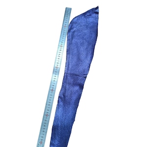 May include: A long, blue fabric sleeve featuring a textured, snakeskin-like pattern. A metal ruler is positioned alongside the sleeve, indicating a total length of approximately 60 cm from the top edge to the bottom hem of the fabric.
