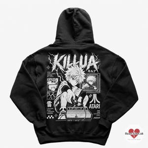 May include: A black hooded sweatshirt featuring a white graphic print on the back. The design displays an anime character named Killua, a retro game console, a television screen with the text PRESS START, and the word ATARI with its logo.