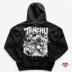 May include: A black hooded sweatshirt featuring a large white graphic print on the back. The design displays two masked figures with swords, Japanese kanji characters, and the text TENCHU, set against a backdrop of a moon and traditional architecture.