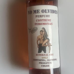 May include: A brown perfume bottle with a gold cap and a white label. The label features the text "NO ME OLVIDES PERFUME CONTIENE FEROMONAS" and an illustration of a couple. Additional text includes "EXTERNAL USE ONLY CONTAINS: ALCOHOL FRAGRANCE COLOR."