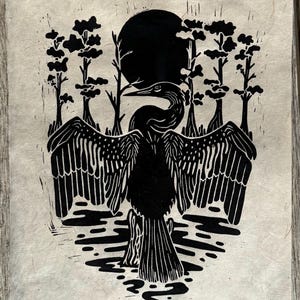 Peut inclure: Estampe en linogravure en noir et blanc représentant un oiseau aux ailes déployées, entouré d'arbres et d'une pleine lune. L'œuvre a un aspect artisanal, avec la texture du papier.