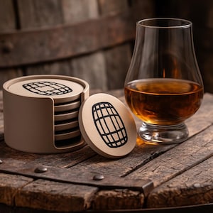 Puede incluir: Un juego de posavasos beige con un diseño de barril negro, junto a un vaso de líquido ámbar. Los posavasos están en un soporte, y uno está colocado por separado. La escena está ambientada sobre una superficie de madera, sugiriendo un bar.