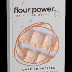 May include: A cookbook titled "flour power." features a white cover with the title in black and the author's name, "BY FOODZIZZLES." The cover showcases bread rolls and the text "OVER 50 RECIPES BREADS, PASTERIES & MORE."