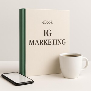 Peut inclure: Un livre crème intitulé "eBook IG MARKETING" avec un dos vert, une tasse à café blanche remplie de liquide foncé et un smartphone noir avec un écran blanc, le tout sur une surface blanche.