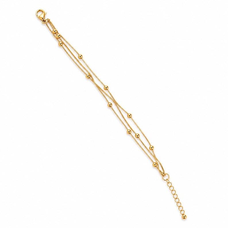 K&ouml;nnte beinhalten: Ein goldfarbenes mehrstr&auml;ngiges Armband mit drei feinen Ketten, die mit kleinen, gleichm&auml;&szlig;ig verteilten goldenen Kugeln verziert sind. Das Armband verf&uuml;gt &uuml;ber einen Karabinerverschluss an einem Ende und eine verstellbare Verl&auml;ngerungskette.