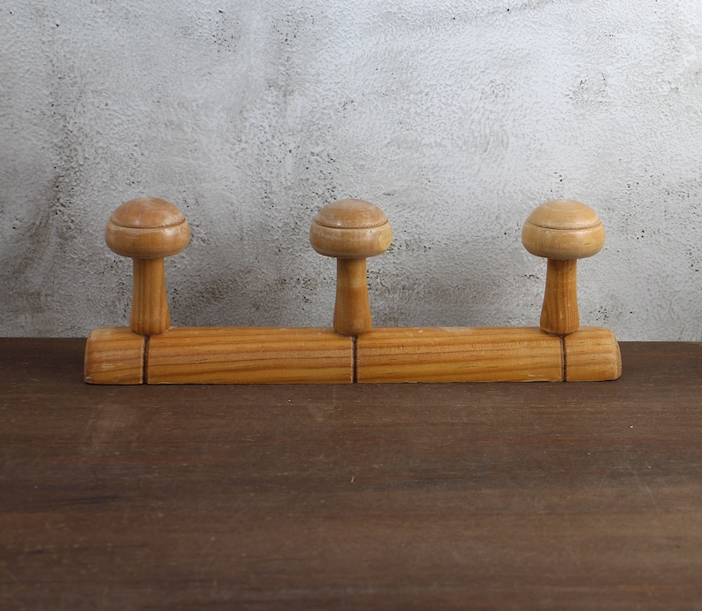 Puede incluir: Un perchero de madera con tres ganchos. El perchero es de madera marr&oacute;n claro y tiene un dise&ntilde;o sencillo.