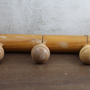 Puede incluir: Perchero de madera con tres pomos redondos. El perchero est&aacute; hecho de madera natural y tiene un aspecto r&uacute;stico.