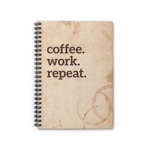 以下が含まれることがあります： ベージュの背景に「coffee. work. repeat.」と茶色で印刷された、スパイラル綴じのノート。コーヒーの染みやリングがあり、コーヒーをテーマにしたデザインを示唆しています。
