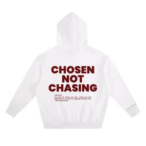 May include: White hoodie with the text "CHOSEN NOT CHASING" in maroon. The hoodie also includes a Bible verse from John 15:16. The hoodie has a hood and long sleeves. The design is centered on the back of the hoodie.
