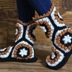 May include: Crocheted black, white and brown slippers with a geometric pattern. The slippers are made with a chunky yarn and have a rounded toe.