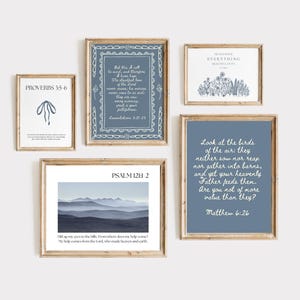 Puede incluir: Una colección de láminas artísticas enmarcadas con citas inspiradoras e imágenes de paisajes. Las láminas presentan una variedad de diseños, incluyendo ilustraciones florales, paisajes montañosos y versículos bíblicos en tonos azules y blancos, enmarcadas en madera.