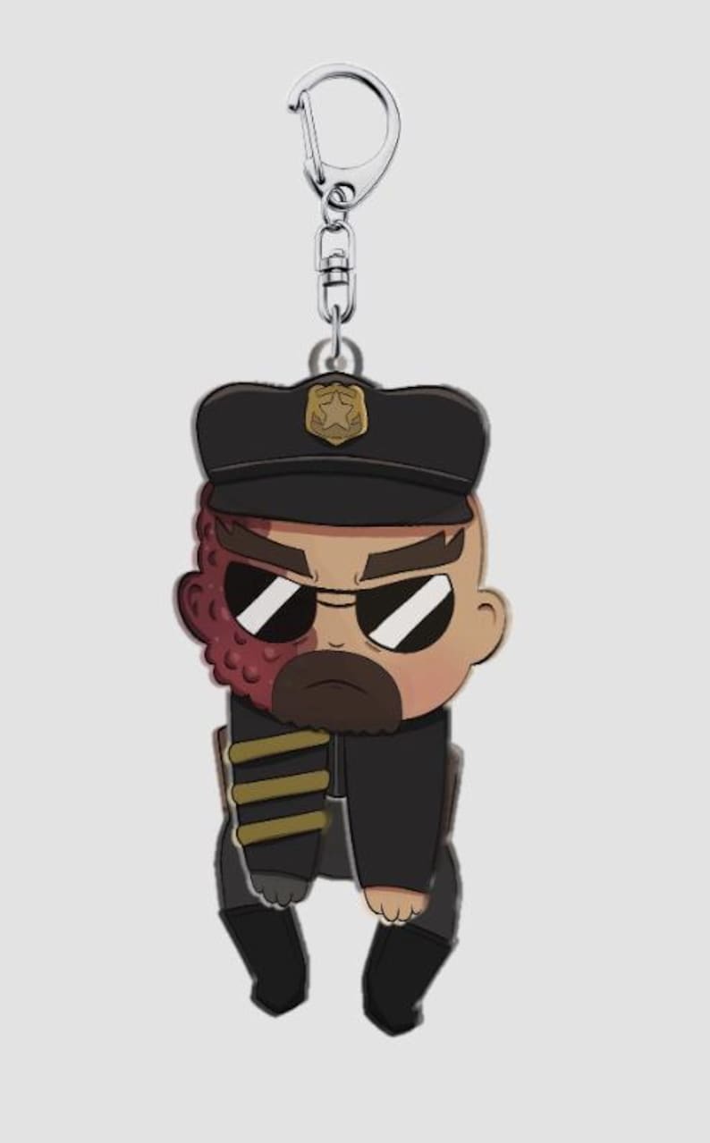 Pode incluir: Um porta-chaves de novidade com um personagem em estilo cartoon em uniforme de pol&iacute;cia. O personagem tem uma express&atilde;o severa, &oacute;culos de sol e uma cicatriz no rosto. O porta-chaves tem um fecho prateado.