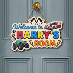 Op de afbeelding: Houten bord met de tekst "Welcome to HARRY'S ROOM" in blauw, rood en oranje. Het bord toont illustraties van een raceauto, monstertruck, vlaggen en bliksemschichten. Het hangt aan een gouden knop met een touw.