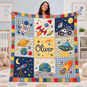 May include: A patchwork quilt featuring space-themed squares with an astronaut, rocket, lunar rover, planets, telescope, UFO, and a comet. The centre square displays the name Oliver in dark blue script, surrounded by stars on a yellow background.