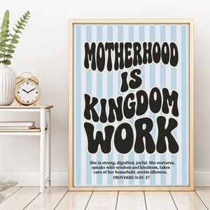 Quadro da parete con la scritta "La maternità è opera del Regno", citazione biblica di Proverbi 31, sfondo a righe blu.