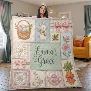 May include: A pastel patchwork quilt with Easter-themed illustrations. The design includes bunnies, Easter eggs in a basket, flowers, bows, and carrots. The name "Emma Grace" is written in cursive in the center of the quilt.